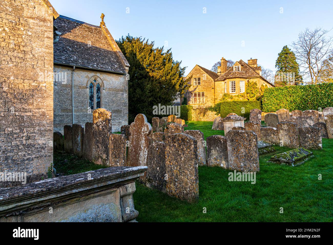 Luce serale sull'Old Rectory vista dal cimitero della chiesa di San Giovanni Battista nel villaggio Cotswold di Great Rissington, Gloucestershire Foto Stock