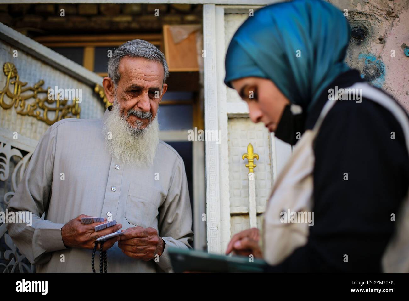 Baghdad, Iraq. 20 novembre 2024. Un ufficiale del censimento sul campo raccoglie dati da un residente durante il primo giorno del censimento nazionale iracheno nella città di Sadr a Baghdad. L'Iraq sta conducendo il suo primo censimento nazionale della popolazione in 37 anni, una mossa che dovrebbe avere un impatto sulla distribuzione delle risorse, che ha riacceso le tensioni tra Baghdad e la regione semi-autonoma del Kurdistan con il timore che un declino della popolazione curda possa ridurre la loro influenza politica e i loro diritti economici. Crediti: Ameer al-Mohammedawi/dpa/Alamy Live News Foto Stock