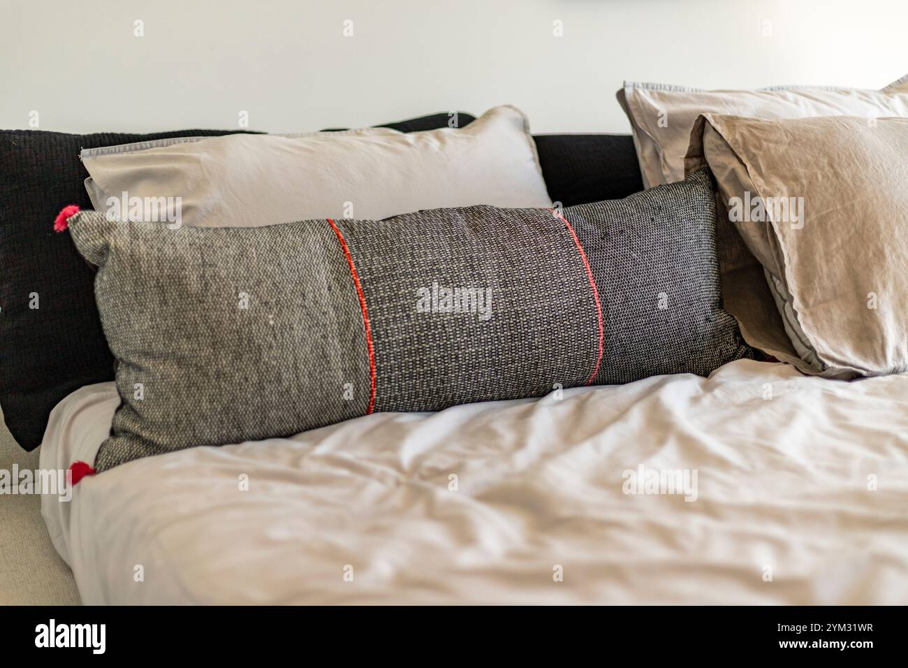 Un cuscino dal design bianco e nero si trova su un letto. Il cuscino è circondato da altri cuscini, creando un'atmosfera intima e confortevole Foto Stock