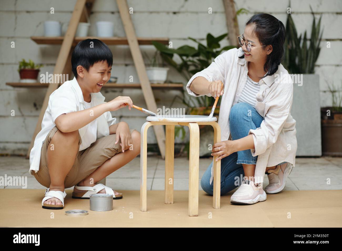 Dipingere insieme una sedia di legno nel Backyard Workshop Foto Stock
