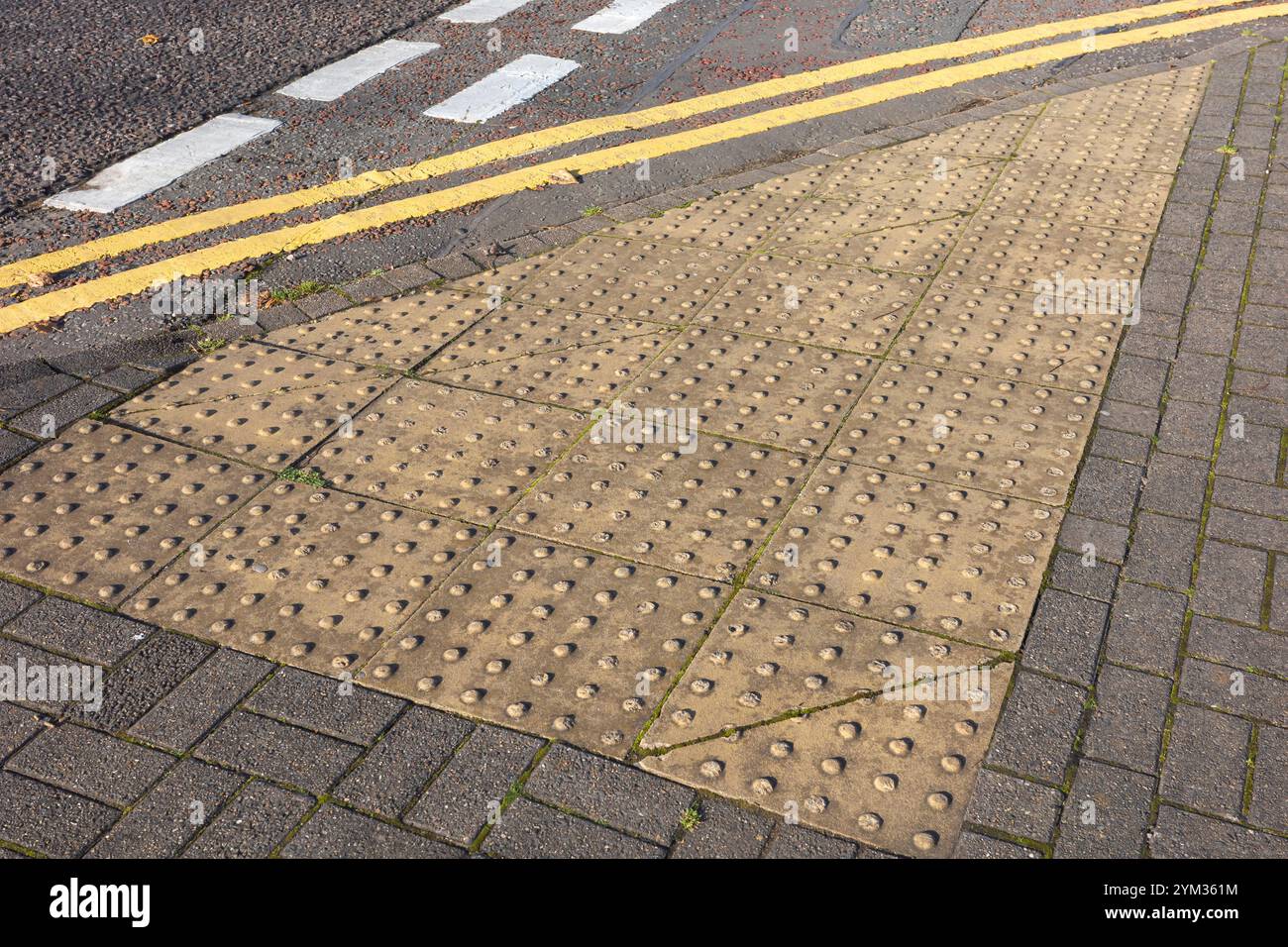 Pavimentazione tattile in corrispondenza di un punto di incrocio all'angolo della strada per i pedoni non vedenti. Foto Stock