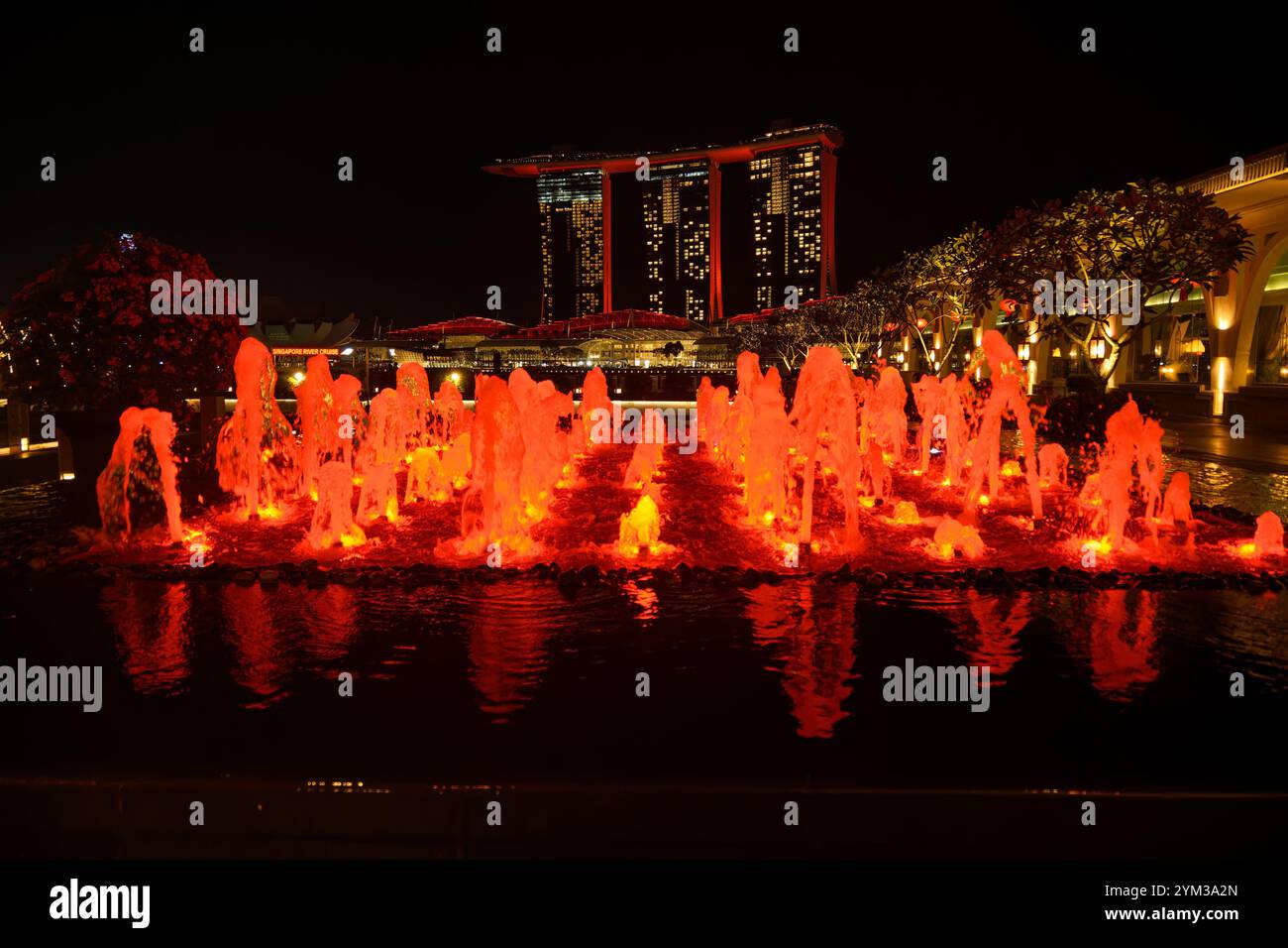 Marina Bay Sands dietro una fontana di Singapore, entrambe illuminate in rosso come buona fortuna per le celebrazioni del Capodanno cinese, in Asia Foto Stock Marina Bay Sands dietro una fontana di Singapore, entrambe illuminate in rosso come buona fortuna per le celebrazioni del Capodanno cinese, in Asia Foto Stock