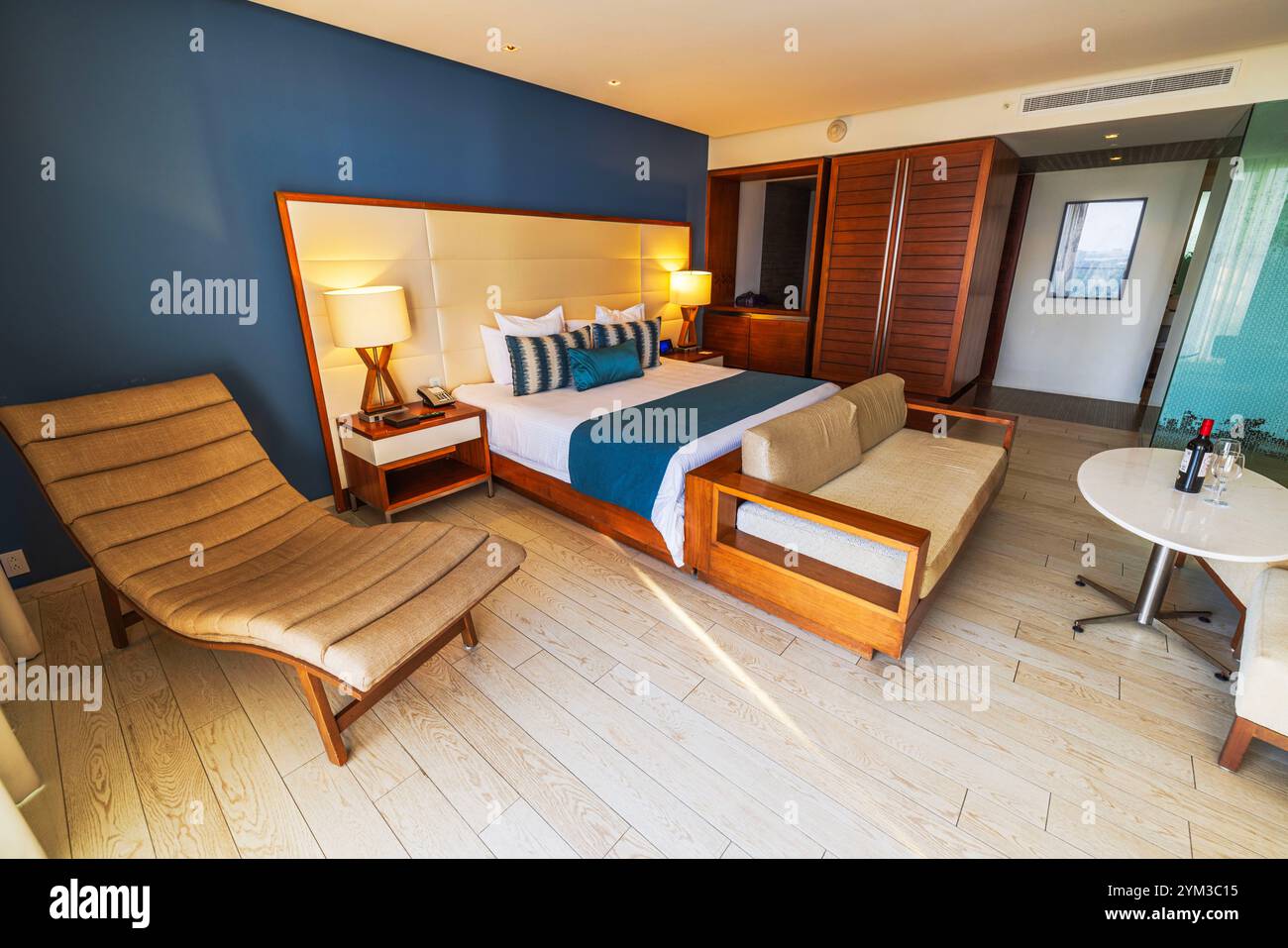 Elegante camera in Messico con arredi moderni in legno, chaise longue, letto spazioso e arredamento minimalista. Cancún. Messico. Foto Stock