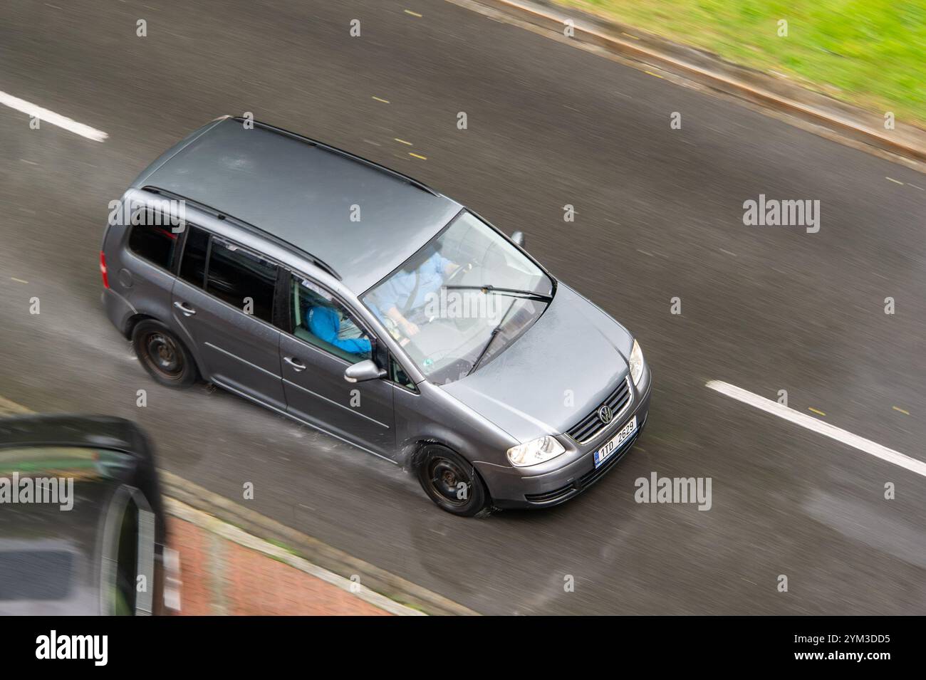 OSTRAVA, CECHIA - 25 MAGGIO 2024: Volkswagen Touran MPV su ruote in acciaio nero, effetto di sfocatura del movimento in caso di pioggia Foto Stock