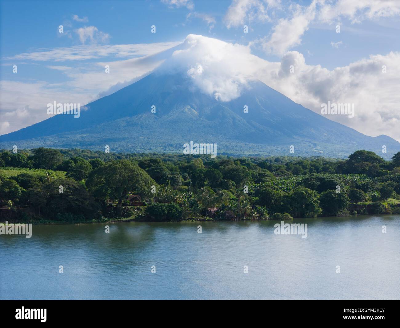 Lo splendido vulcano sorge maestosamente sopra il verde e le acque calme, mostrando la bellezza della natura sotto il cielo limpido. Foto Stock