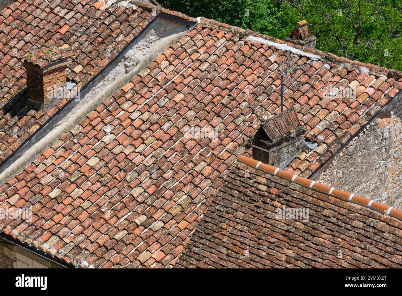 Tradizionali tegole arancioni francesi fatte a mano sui tetti in Francia. A sinistra il cosiddetto canale delle tuille e sul tetto a destra la piastra delle tuille Foto Stock