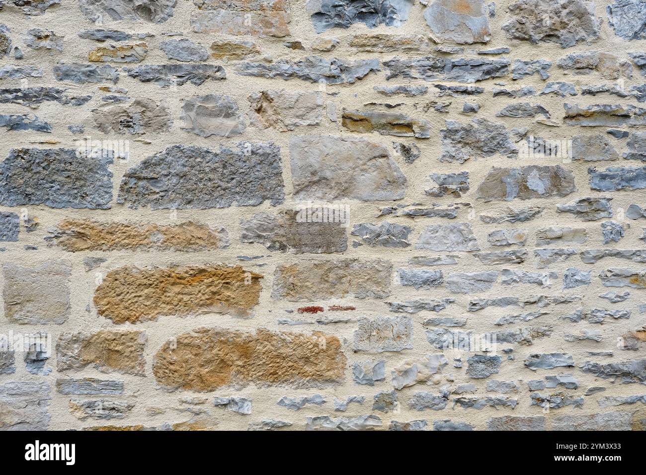 Sfondo di un muro in pietra naturale o arenaria in muratura con cemento nel sud della Francia. Immagine dettagliata della trama della pietra in beige, marrone, grigio e blu Foto Stock