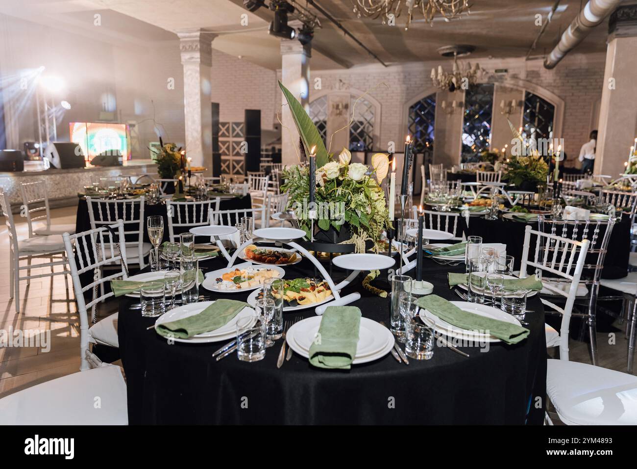 Elegante sala per banchetti con centrotavola floreale, candele e tavoli eleganti Foto Stock