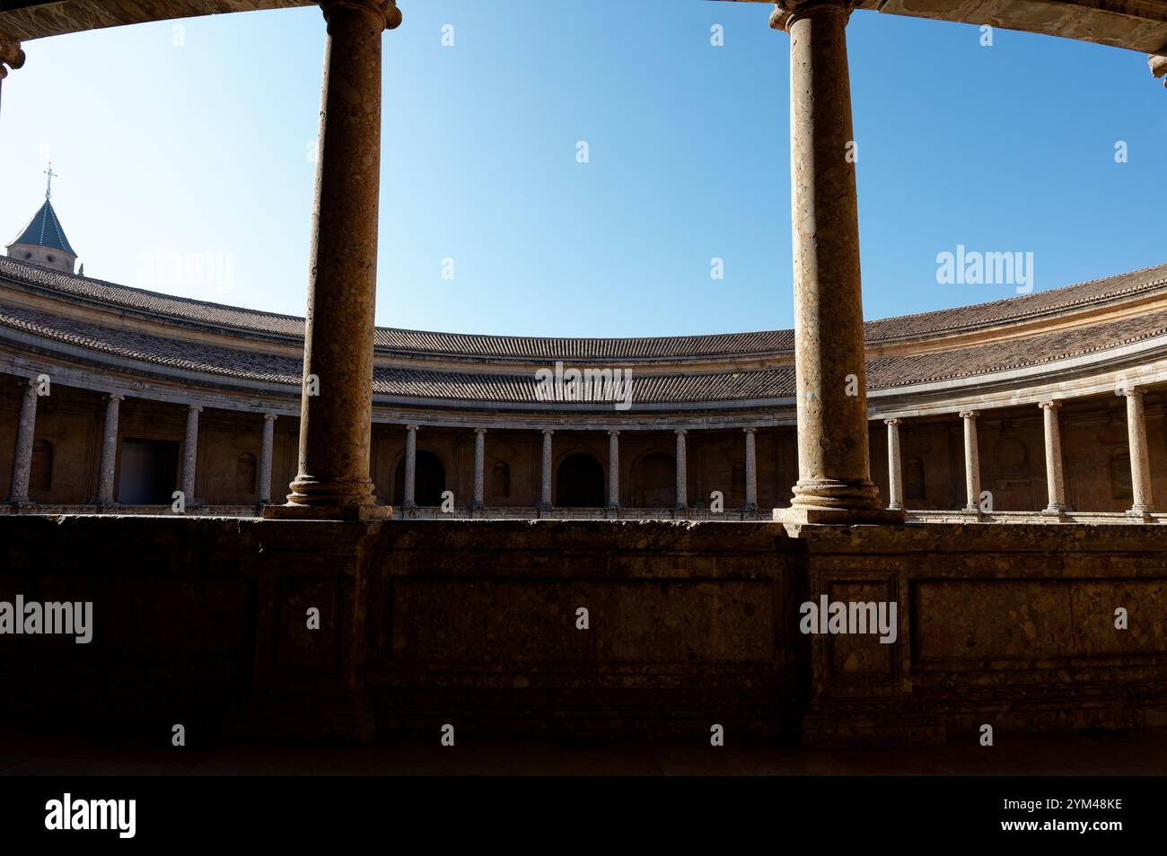 Il cortile colonnato del Palazzo di Carlo V all'Alhambra, incorniciato da pilastri di pietra sotto un cielo azzurro Foto Stock