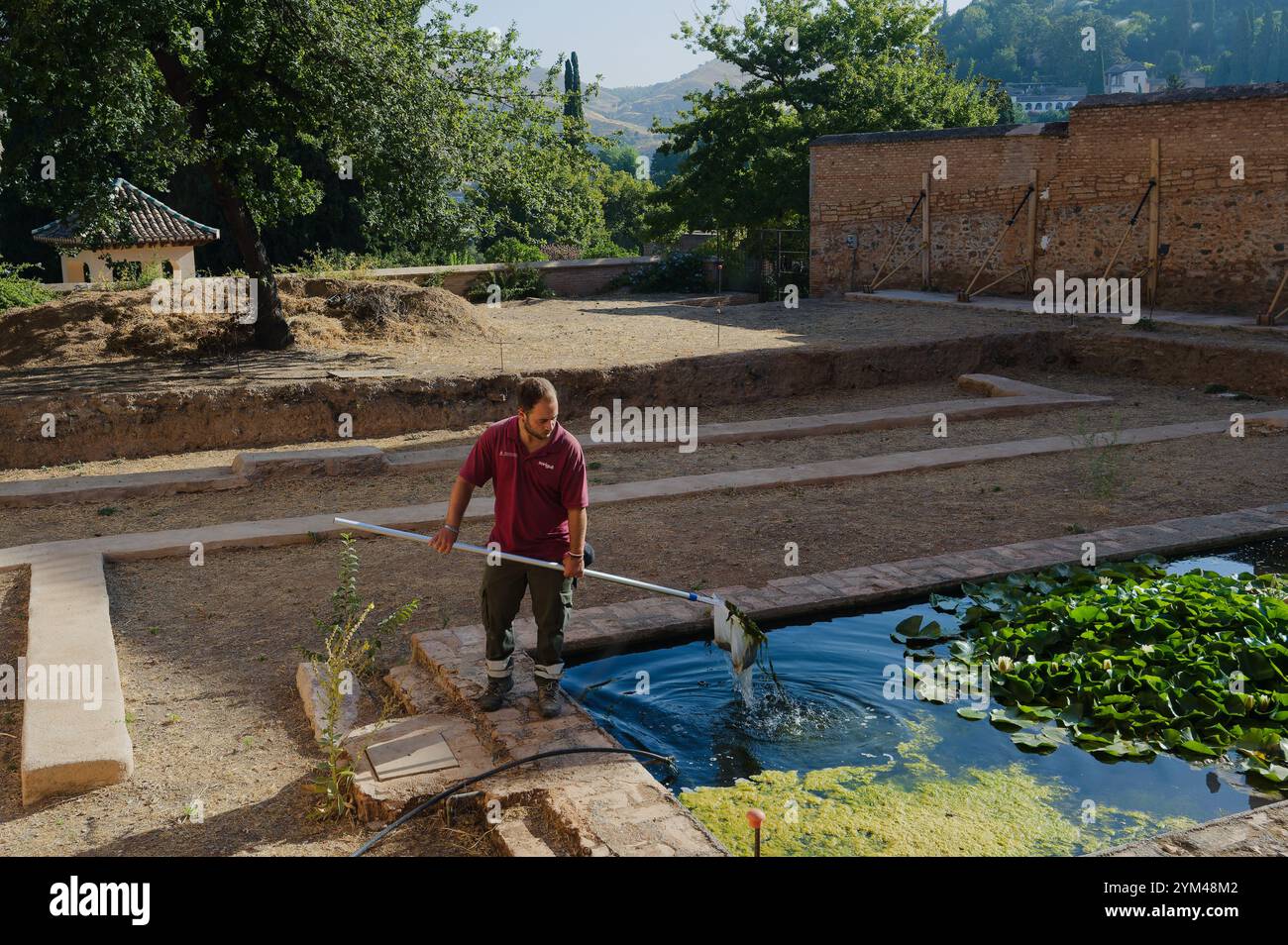 Un giardiniere pulisce un elemento d'acqua sereno nell'Alhambra Foto Stock