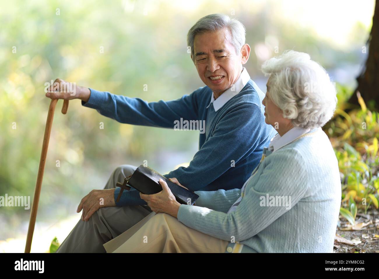 Una coppia anziana che parla tra di loro tenendo una Bibbia Foto Stock