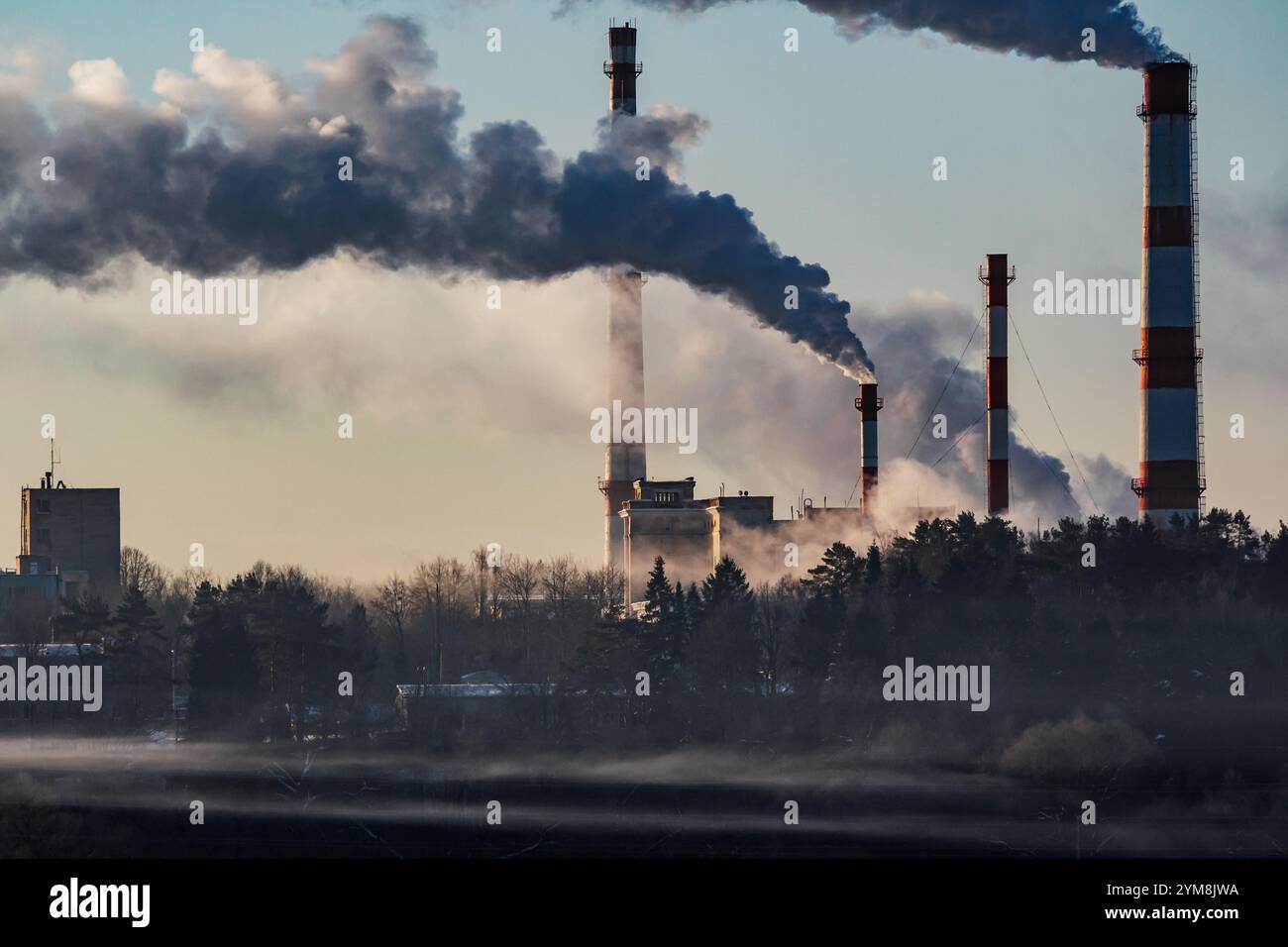 Camini di caldaia molto affumicati in una giornata invernale, paesaggio industriale Foto Stock