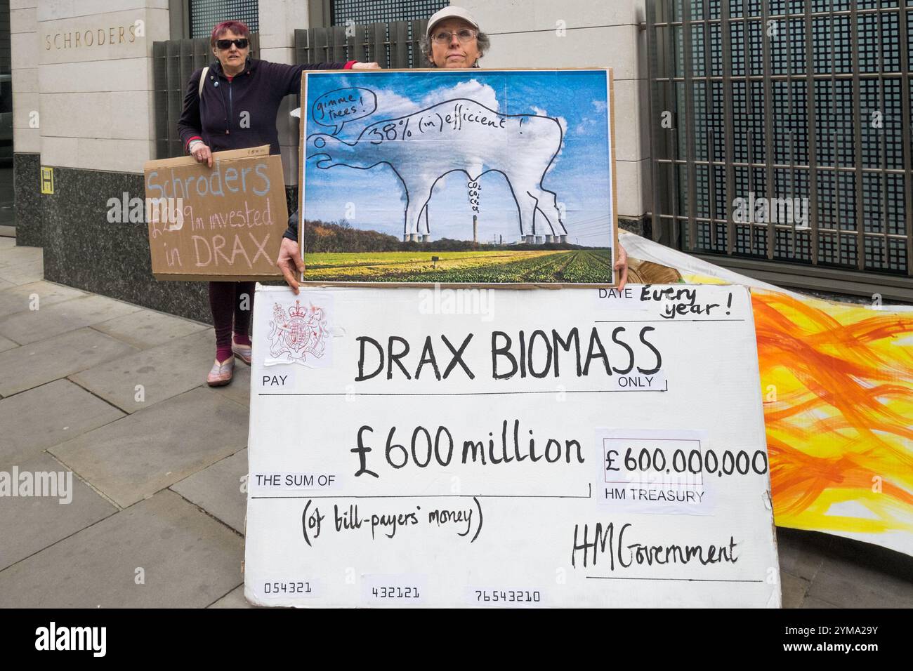 Londra, Regno Unito. 13 aprile 2017. Gli attivisti ambientali di Biofuelwatch e Axe Drax protestano fuori dagli uffici di Schroders e Invesco, i principali azionisti di Drax, la centrale elettrica più grande e inquinante del Regno Unito&#8217. Un assegno gigante di 600 milioni di sterline sottolinea che Drax riceve un enorme sussidio giornaliero di 1,5 milioni di sterline dalle nostre bollette elettriche destinate a finanziare energia rinnovabile pulita, nonostante studi scientifici dimostrino che bruciare legno è disastroso per l'ambiente, producendo grandi quantità di anidride carbonica quando bruciato ed eliminando per molti anni la capacità delle foreste che vengono abbattute per assorbire Foto Stock