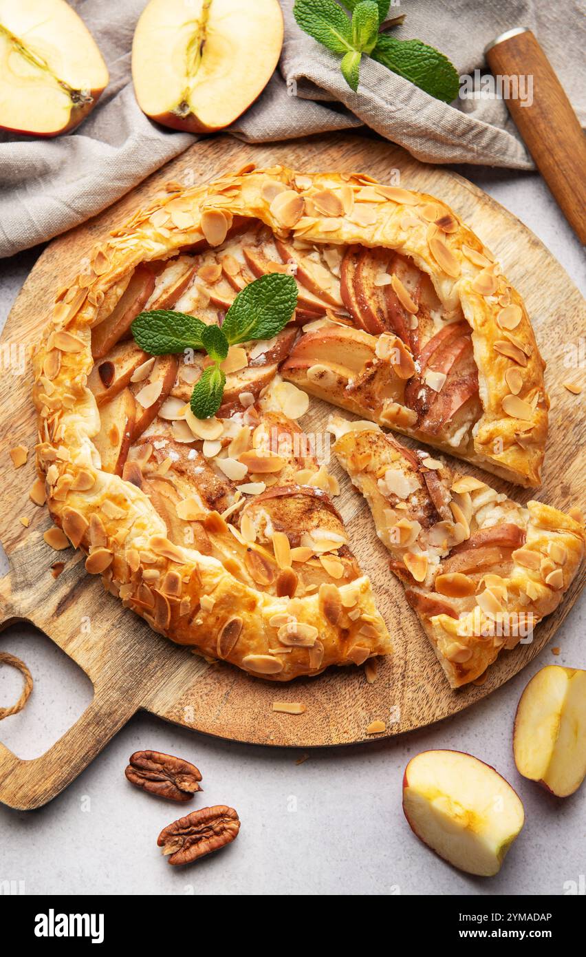 galette di mele appena sfornata, decorata con scaglie di mandorle e foglie di menta, servita su una tavola di legno Foto Stock