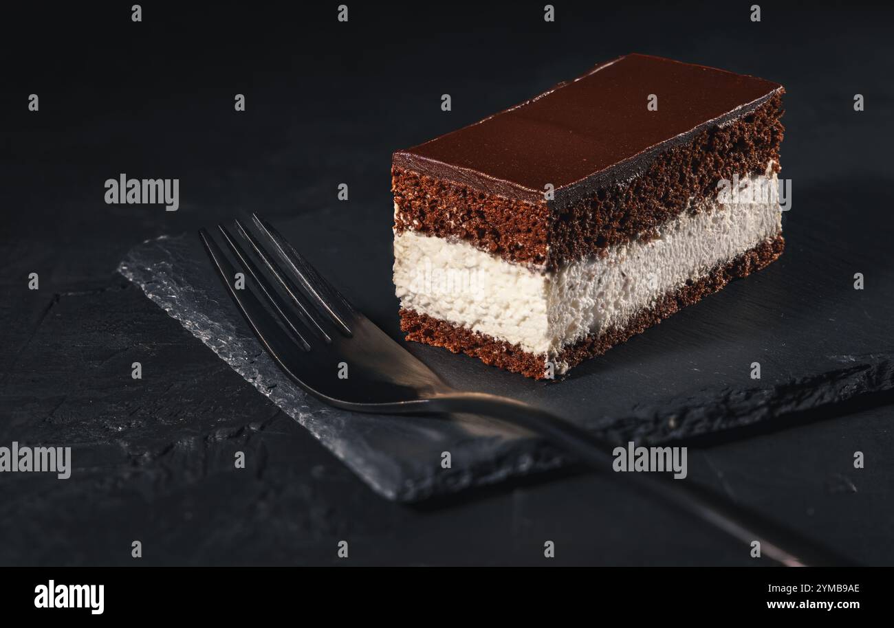 Torta al cioccolato, dolce cremoso a strati di cacao su un piatto di ardesia con fondo scuro Foto Stock