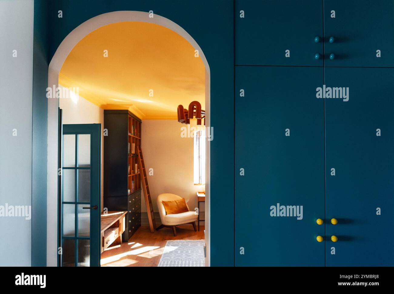 Interni eleganti e accoglienti del soggiorno. Una porta ad arco con una parete blu brillante e un guardaroba incorporato. Design a contrasto con il legno fu naturale Foto Stock