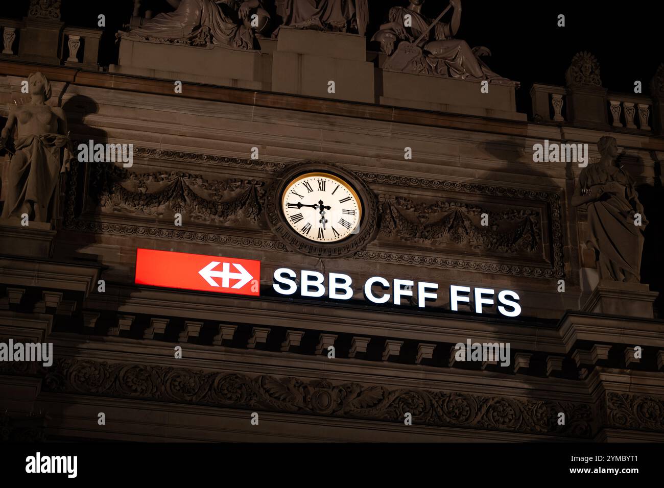 18-11-2024, Zurigo, Svizzera. Ferrovie svizzere FFS CFF FFS cartello o emblema illuminato e grande orologio in cima all'ingresso dell'edificio della stazione centrale a NEG Foto Stock