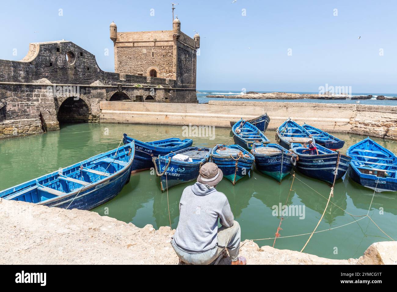 In un bacino riparato del porto peschereccio di Essaouira, alcune piccole imbarcazioni da pesca, di un blu intenso, riposano dopo aver messo in mare Foto Stock