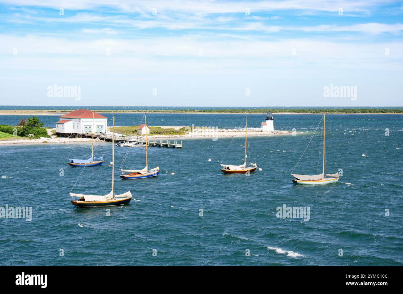 Barche a vela ancorate in mare vicino al faro e al molo Foto Stock