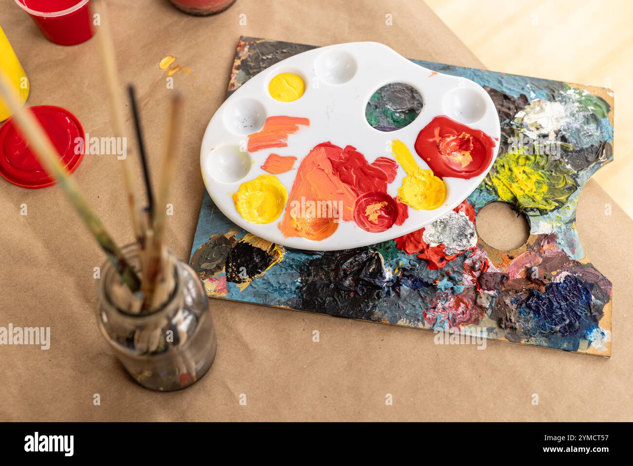 Tavolozza colorata e pennelli sul tavolo, pronti per progetti artistici creativi, a casa Foto Stock