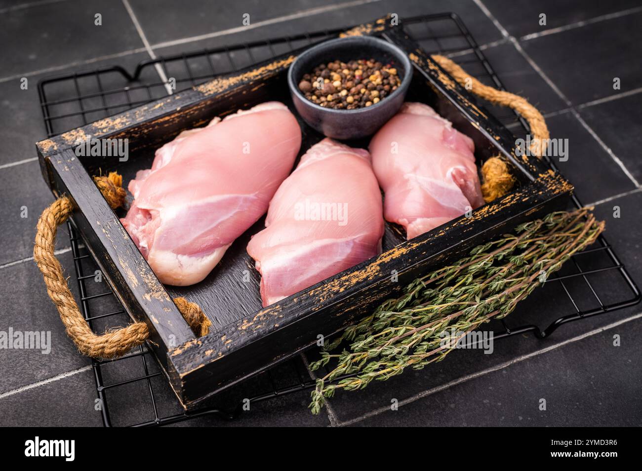 Filetti di cosce di pollo crude in un vassoio di legno fondo nero. vista dall'alto. Foto Stock