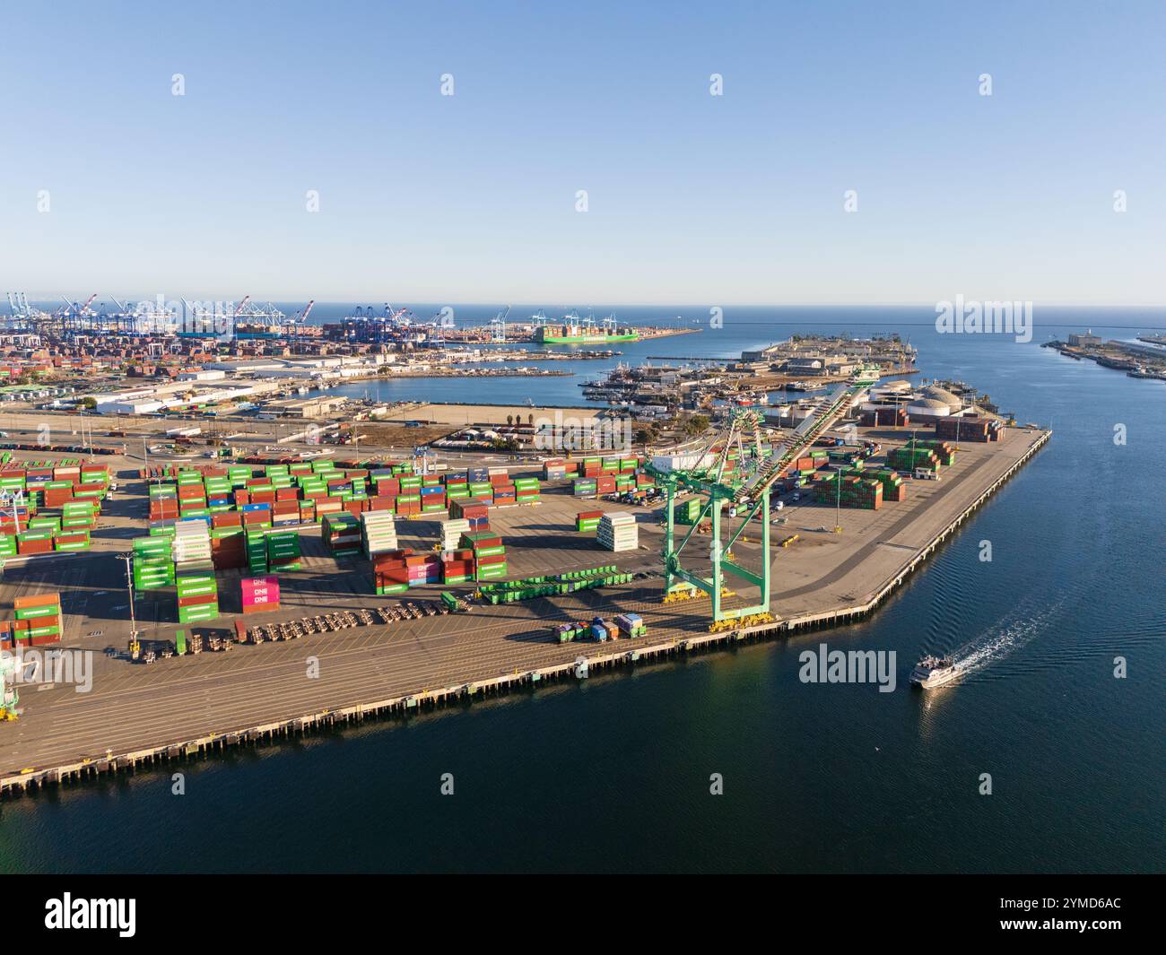 Vista aerea ad alta angolazione dei terminali per container, delle gru portuali e di una barca che naviga nel canale al porto di Long Beach, California Foto Stock
