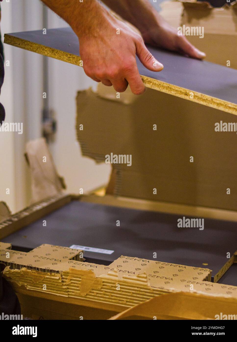 Disimballaggio e assemblaggio di mobili: Movimentazione manuale di pannelli in legno dalla confezione. Foto di alta qualità Foto Stock