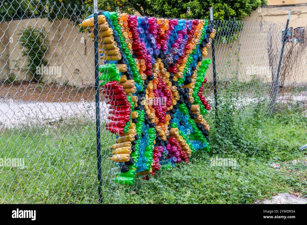 Un'installazione artistica realizzata con materiali riciclati è appesa a una recinzione in maglia di ferro a Kaya Wilson Godett, nel quartiere Otrabanda di Willemstad, Curaçao. Otrabanda fa parte del sito del patrimonio mondiale UNESCO della città; durante il festival annuale KayaKaya vengono create opere di street art negli spazi pubblici. Foto Stock