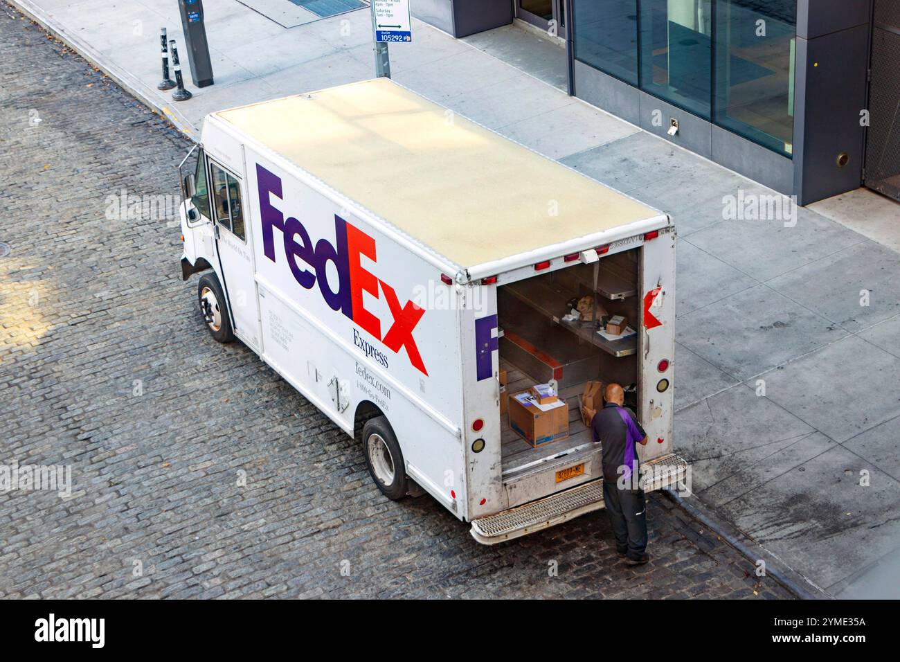 Il furgone FedEx Express è parcheggiato su una strada della città con vetrine e viene scaricato Foto Stock