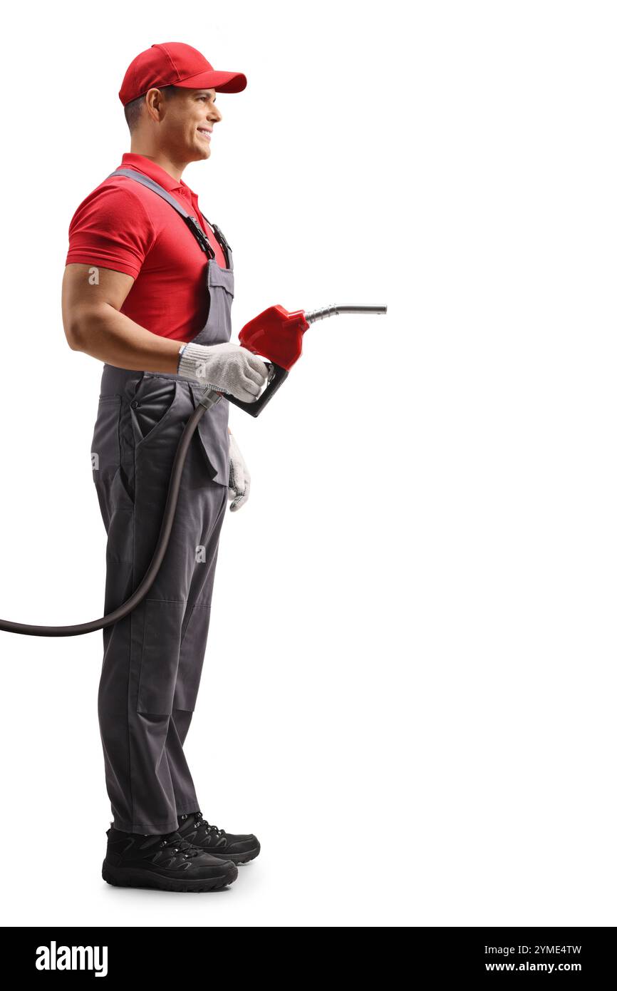 Immagine del profilo a tutta lunghezza di un lavoratore di una stazione di servizio con una pistola a benzina di rifornimento isolata su sfondo bianco Foto Stock