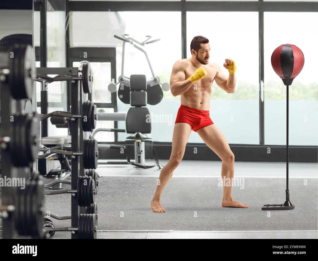 Ripresa completa di un giovane con pantaloncini rossi che pratica kickboxing in palestra Foto Stock