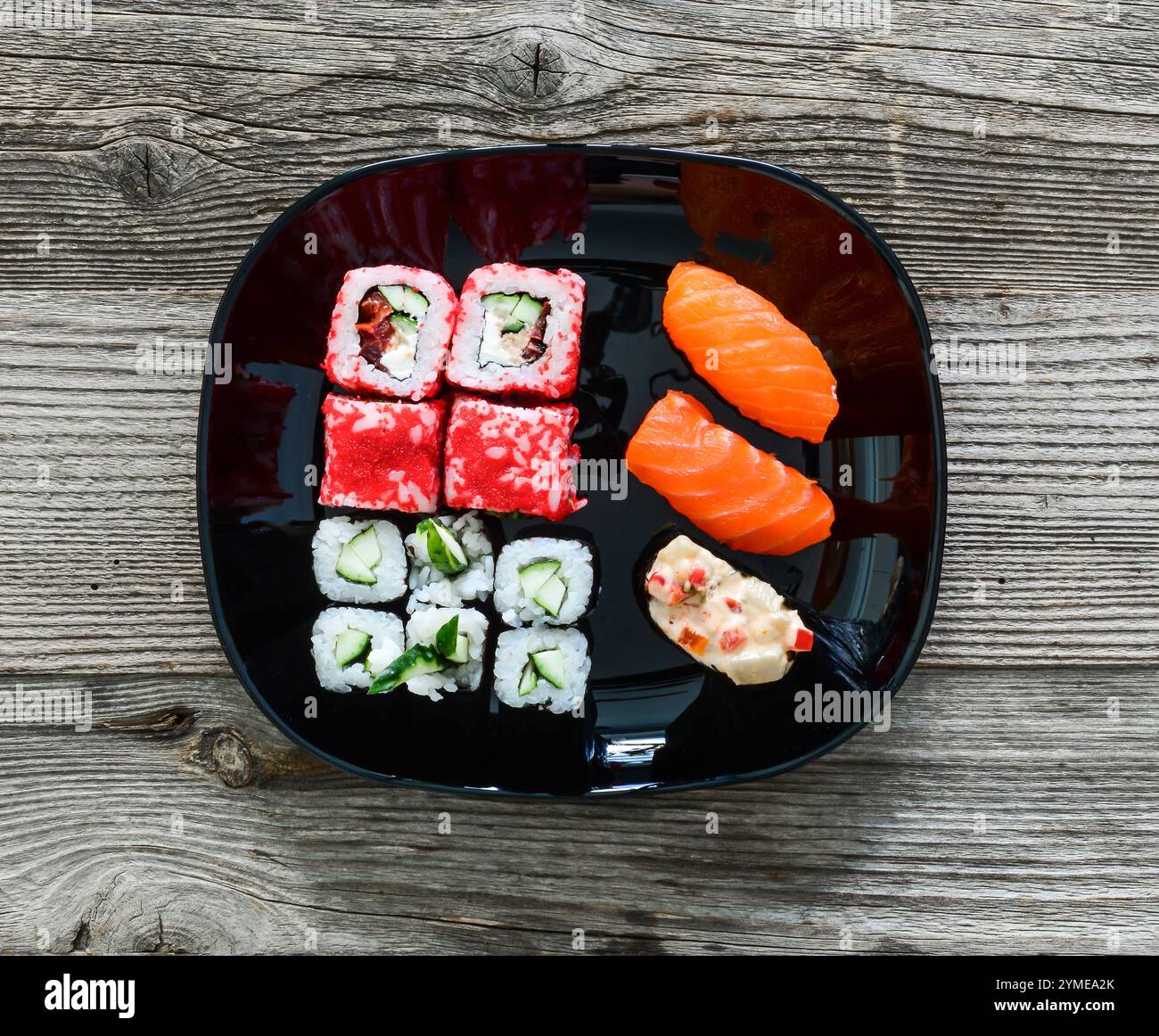 vari sushi su piatto nero su sfondo di legno Foto Stock