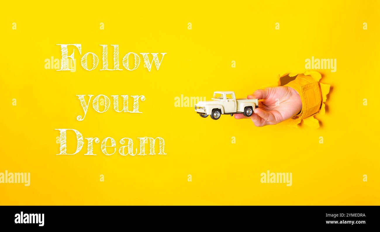 Tenere a mano un camion giocattolo con le parole Segui il tuo sogno scritto sotto di esso. Concetto di speranza e incoraggiamento per perseguire i propri sogni Foto Stock