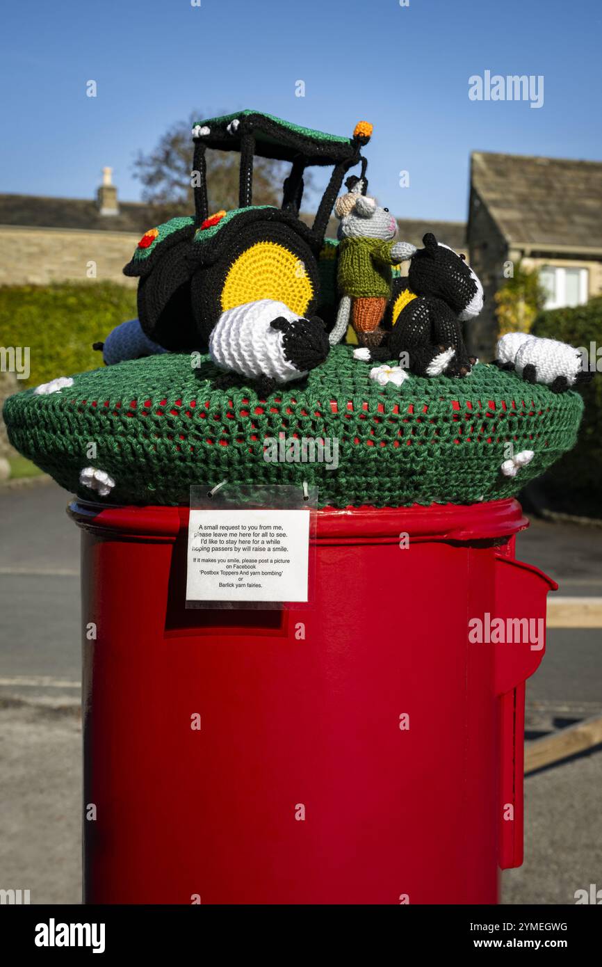 Primo piano di una scatola rossa per bombe in filato (scena agricola, Street art decorativa con bombe in filato, etichetta) - Bolton Abbey Village, North Yorkshire, Inghilterra, Regno Unito. Foto Stock