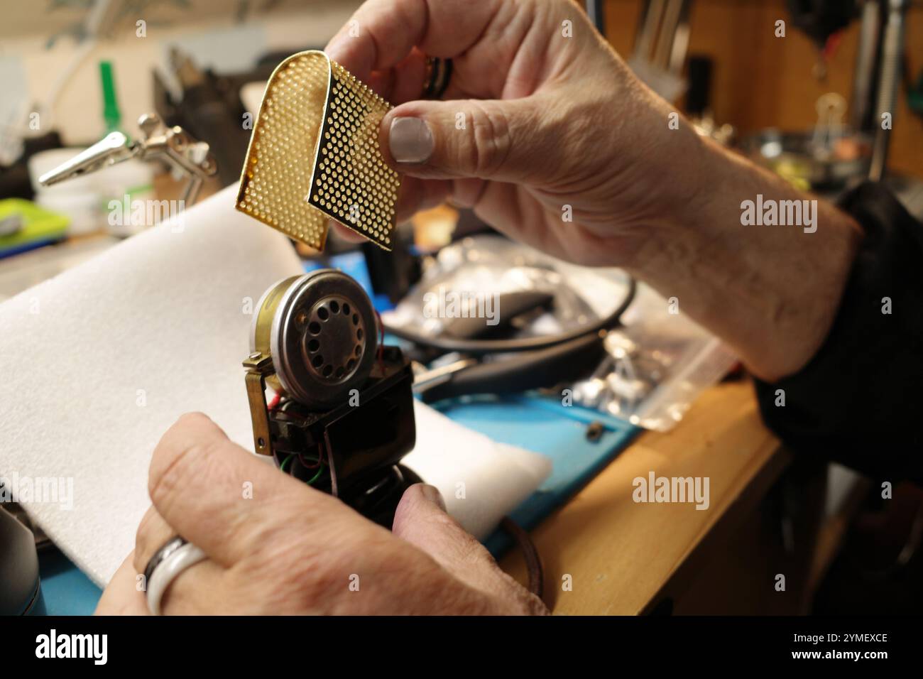 Le mani di un vecchio che ripara un microfono altrettanto vecchio Foto Stock