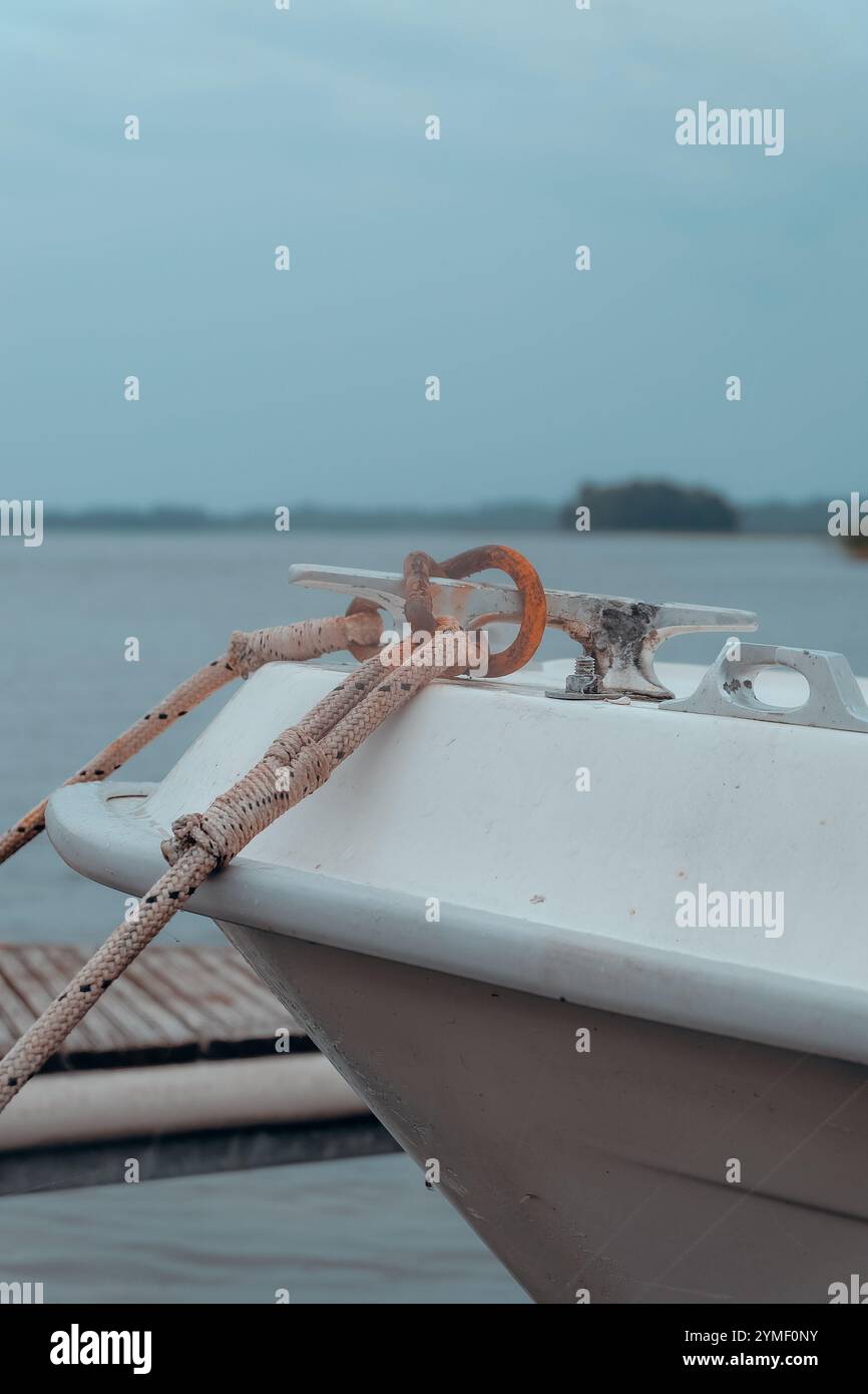 Un tranquillo molo con barche ormeggiate sotto un cielo calmo e coperto, che evoca tranquillità e solitudine in mezzo a un vasto orizzonte d'acqua Foto Stock