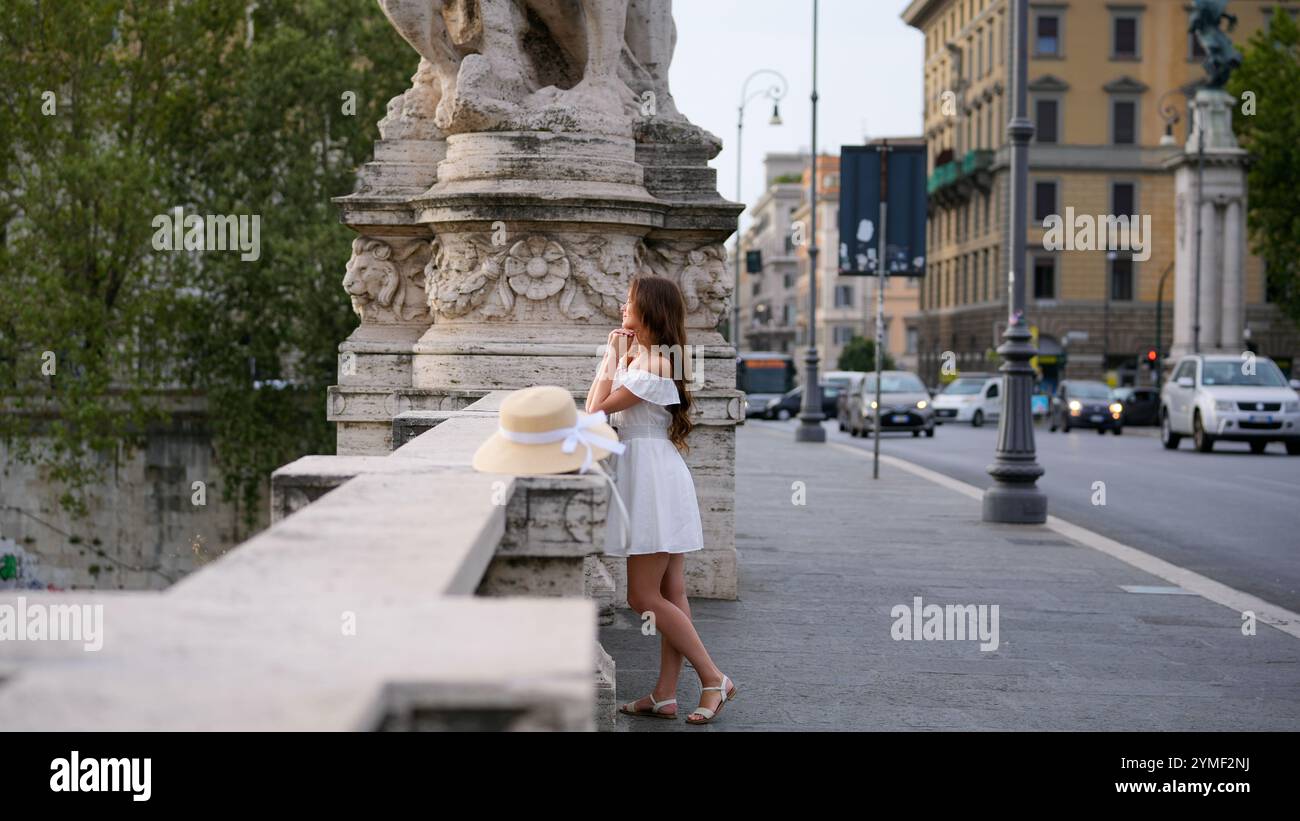 Bella ragazza che ammira l'architettura mentre si trova su un ponte a Roma, Italia Foto Stock