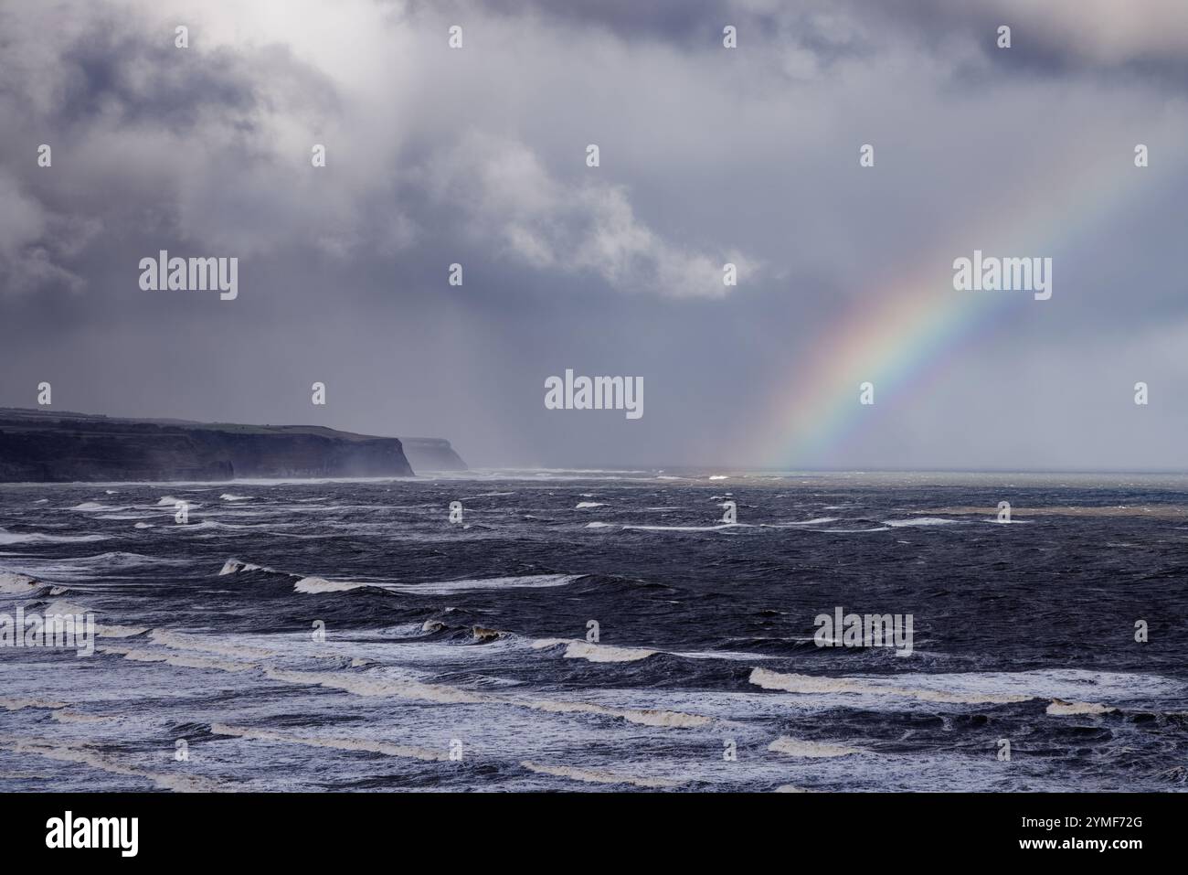 Arcobaleno tra le nuvole tempestose sul mare a Whitby, North Yorkshire, Inghilterra. Foto Stock