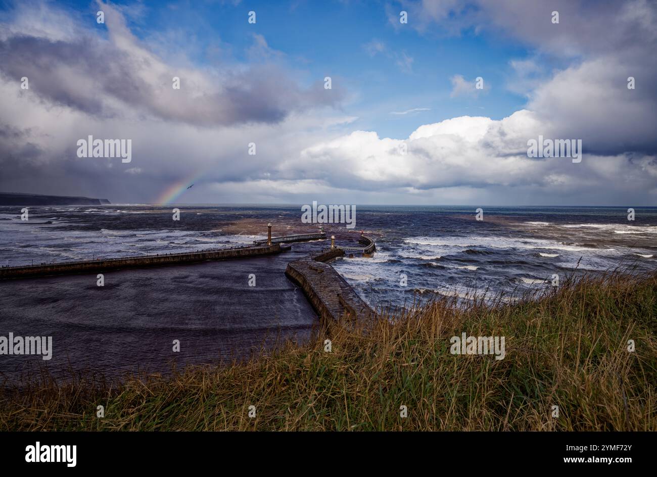 Raccogliendo nuvole di pioggia e arcobaleno sul mare a Whitby Harbour, Inghilterra. Foto Stock