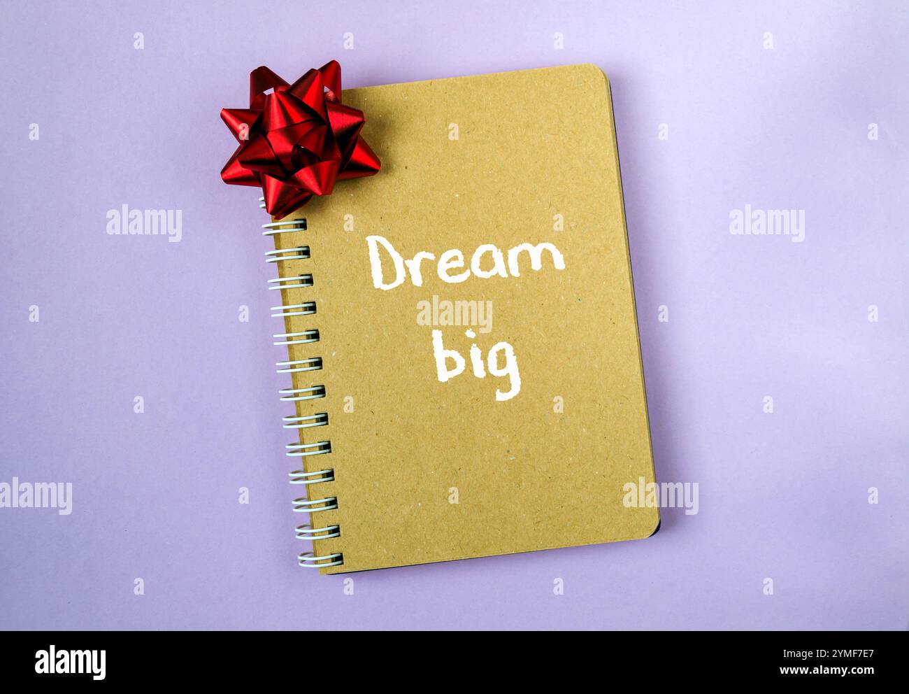 Taccuino con rilegatura a spirale con un fiocco rosso sulla parte superiore e le parole sognano in grande, scritte in bianco Foto Stock