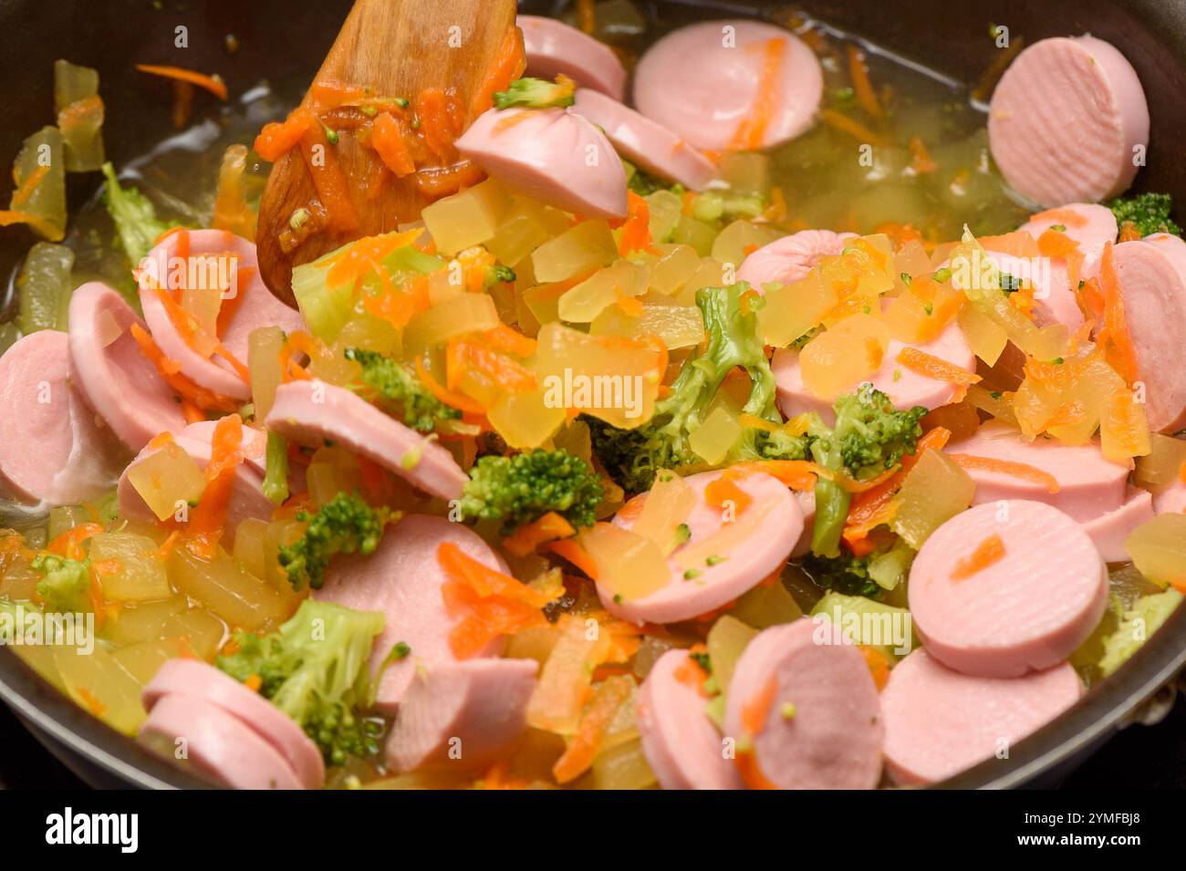 Primo piano di cottura dello stufato di verdure con salsicce affettate. Cucina casalinga. Foto Stock