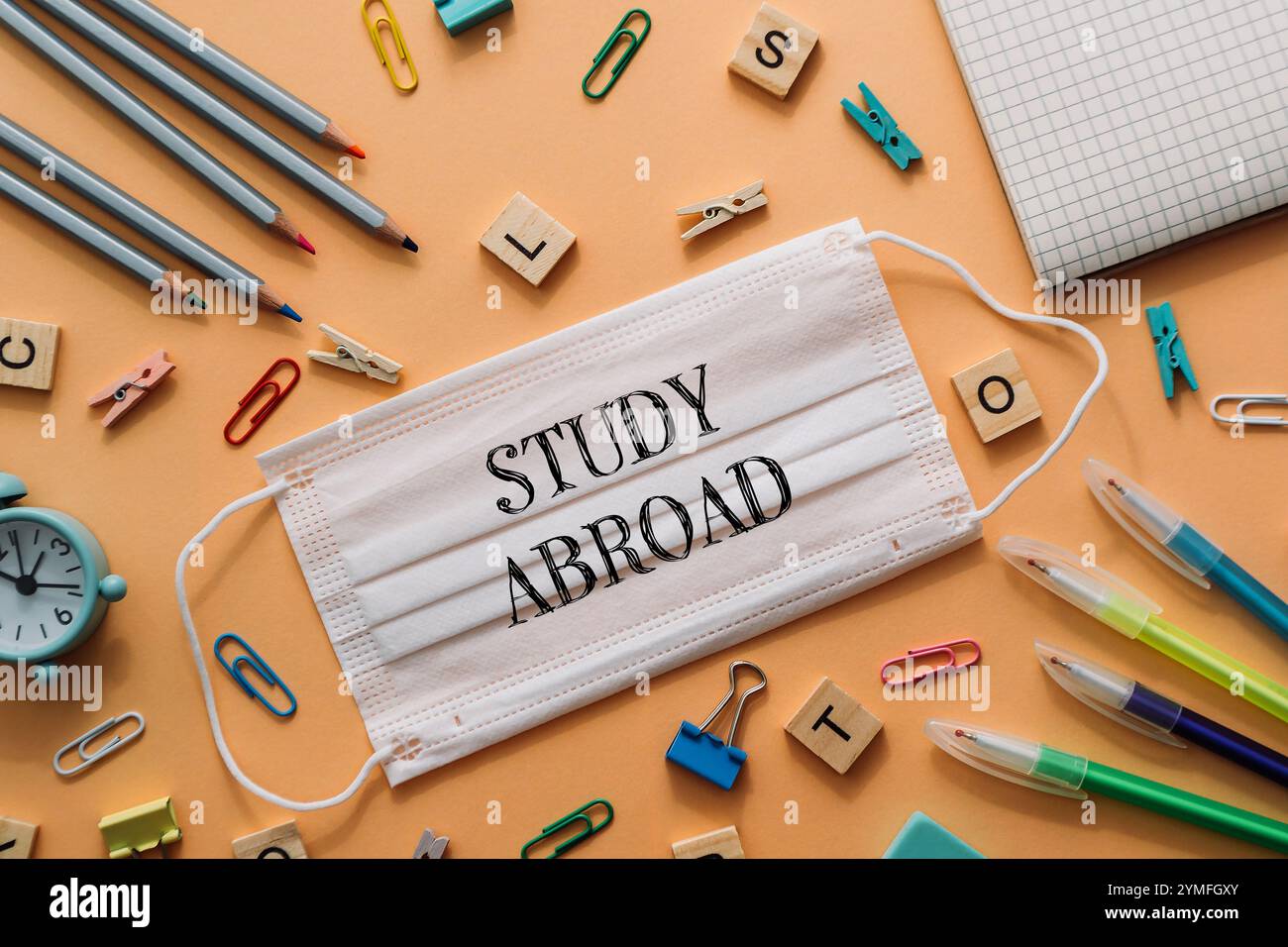 Una maschera bianca con la parola studio su di essa è posizionata su un tavolo con varie forniture per ufficio. Concetto di apprendimento e produttività, in quanto la maschera è associa Foto Stock