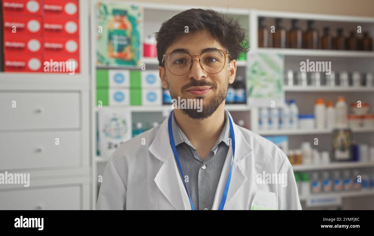 Bell'uomo arabo con occhiali e barba che indossa un camice da laboratorio in un moderno ambiente da farmacia Foto Stock