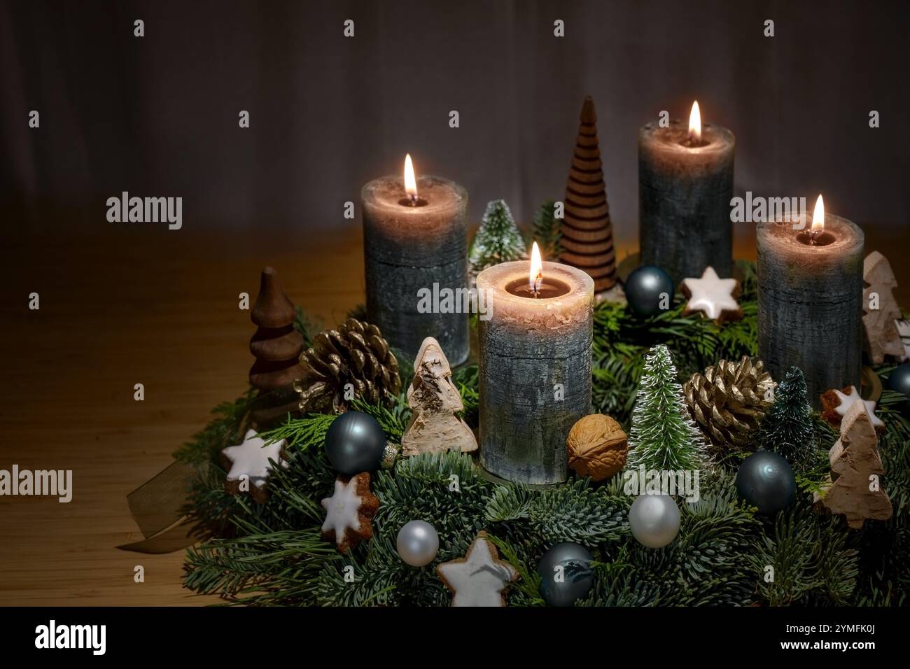 Corona dell'Avvento con quattro candele marroni accese e decorazioni natalizie come baule, coni e stelle alla cannella su sfondo scuro, copia spazio, selec Foto Stock
