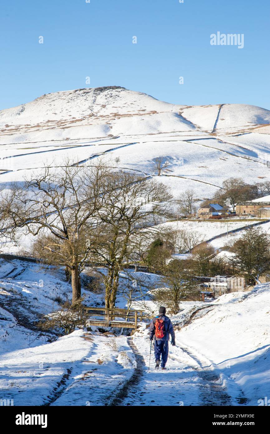 Uomo che cammina da solo con lo zaino in spalla in un paesaggio invernale innevato del Cheshire Peak District nel ruscello di Cumberland, Wildboarclough, verso Shutlingsloe Hill Foto Stock