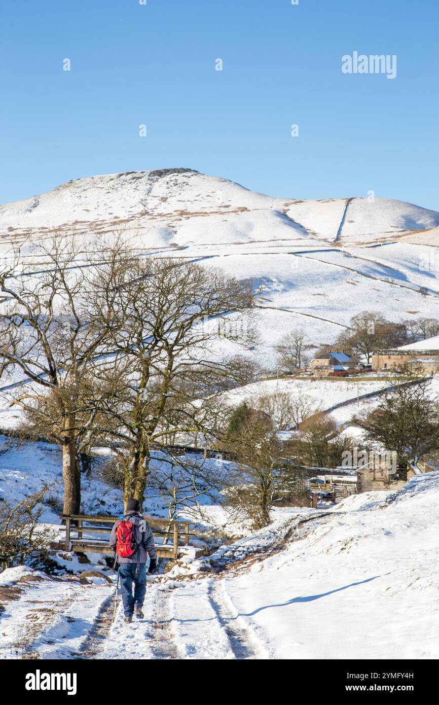 Uomo che cammina da solo con lo zaino in spalla in un paesaggio invernale innevato del Cheshire Peak District nel ruscello di Cumberland, Wildboarclough, verso Shutlingsloe Hill Foto Stock