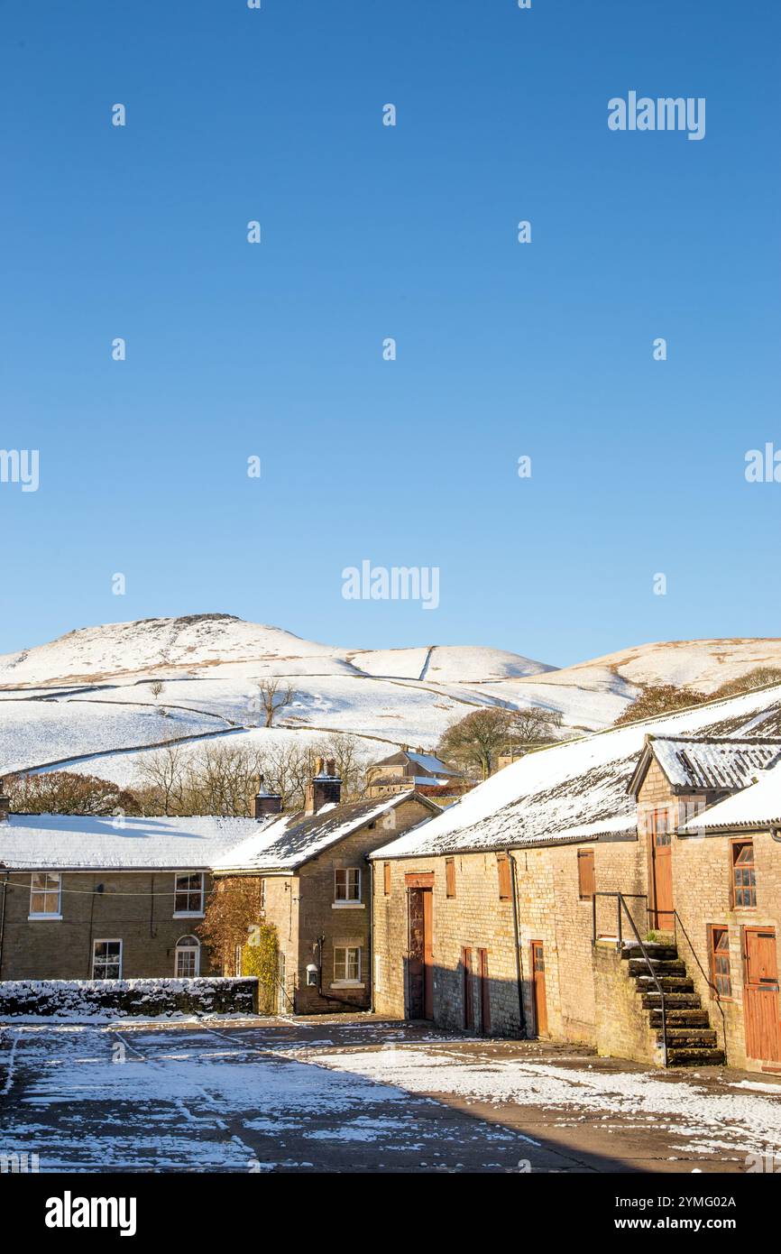 Il paesaggio invernale del Cheshire Peak District è coperto di neve dopo una forte tempesta di neve con una fattoria e edifici agricoli e la collina Shutlingsloe che torreggia sopra Foto Stock