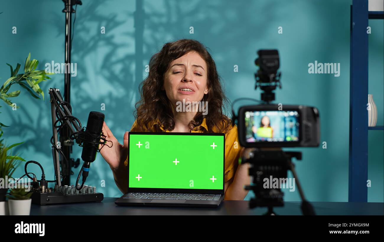 Presentatore di spettacoli online che esegue contenuti di diboxing su un computer portatile con schermo isolato e filma con una fotocamera professionale. Esperto di tecnologia che esegue il posizionamento dei prodotti Chroma key per notebook, registrazione con attrezzatura avanzata, fotocamera A. Foto Stock