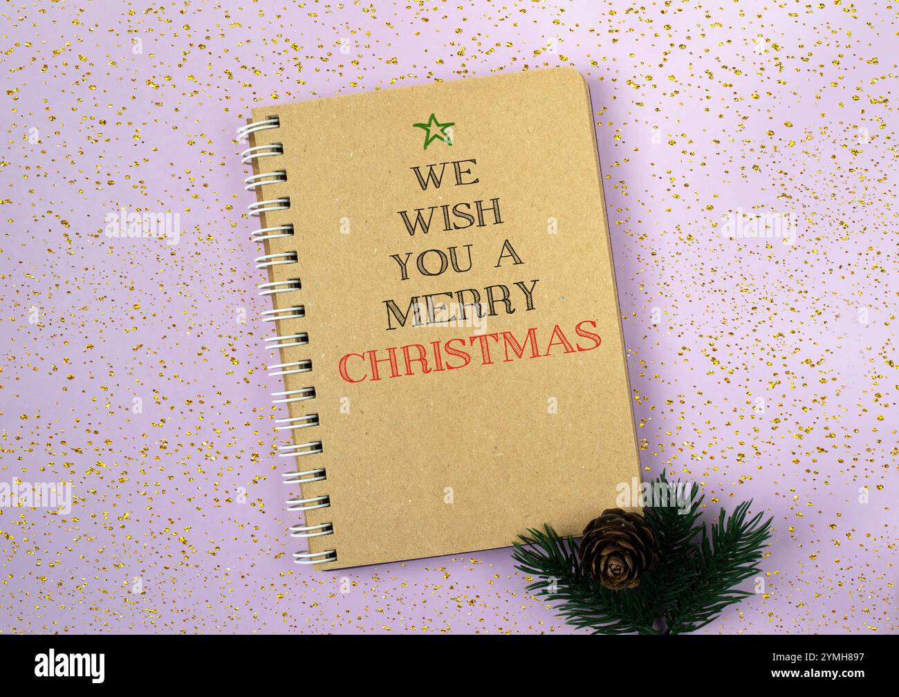 Un notebook dorato con un saluto natalizio circondato da un arredamento minimalista, perfetto per i temi di Natale e Capodanno Foto Stock