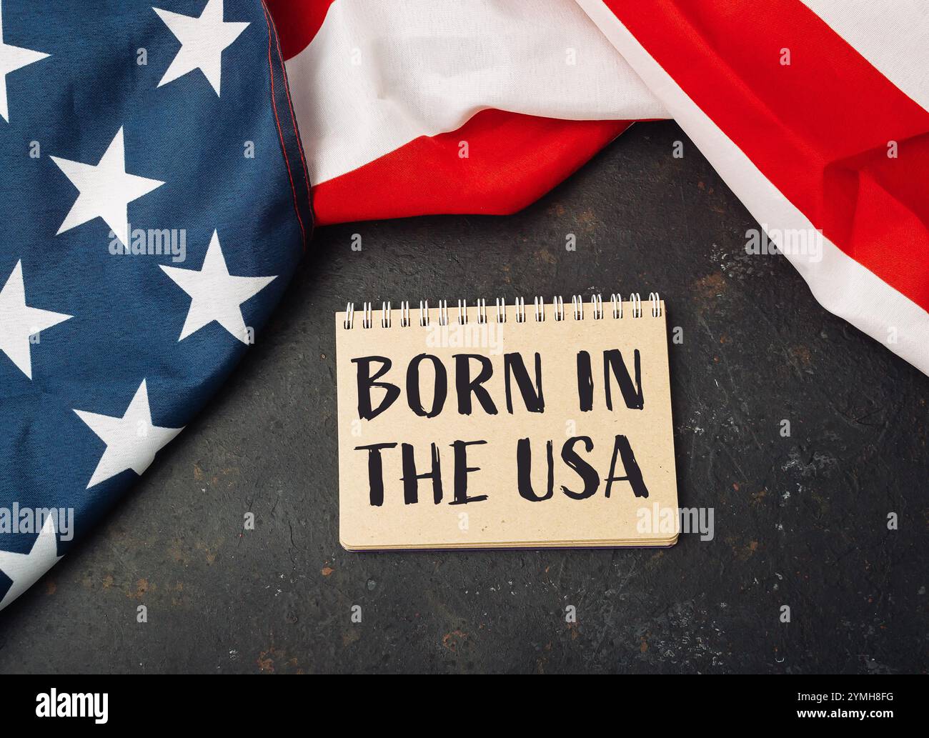 Un pezzo di carta con le parole nate negli Stati Uniti scritte sopra. La carta è posta sopra una bandiera americana rossa e bianca Foto Stock